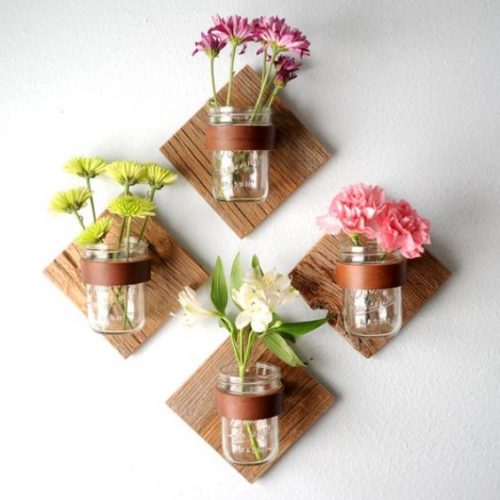 Jars of jam used as flower pots on their wall mounts